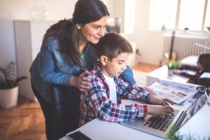 Mother helps son how to use a lap top and internet